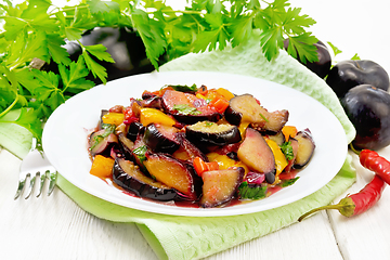 Image showing Eggplant with plums in plate on board