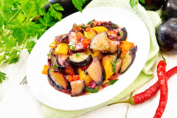 Image showing Eggplant with plums in plate on napkin