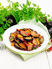 Image showing Eggplant with plums in plate on white board