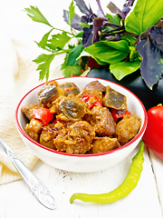 Image showing Meat with eggplant and pepper in bowl on wooden board