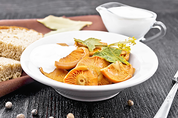 Image showing Mushrooms salted with sour cream in plate on dark board