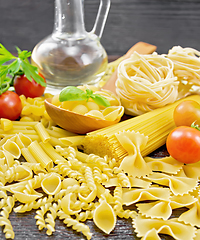 Image showing Pasta different with oil and tomatoes on dark board