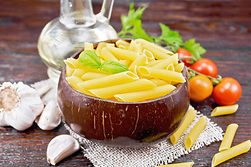 Image showing Penne in bowl of coconut with vegetables on wooden board