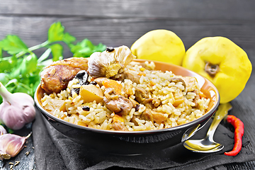 Image showing Pilaf with duck and quince in plate on dark board