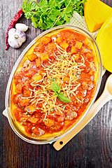 Image showing Porridge corn with meat and vegetables in roaster on dark board 