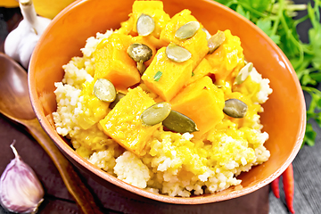 Image showing Porridge millet with spicy pumpkin in clay bowl on dark board