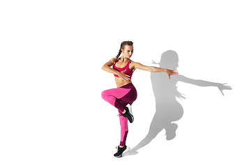 Image showing Beautiful young female athlete practicing on white studio background with shadows