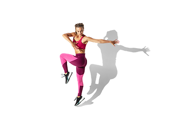 Image showing Beautiful young female athlete practicing on white studio background with shadows