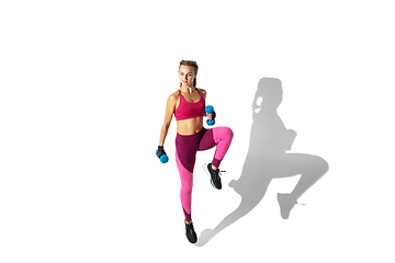 Image showing Beautiful young female athlete practicing on white studio background with shadows