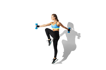 Image showing Beautiful young female athlete practicing on white studio background with shadows