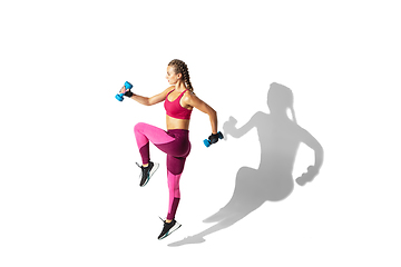 Image showing Beautiful young female athlete practicing on white studio background with shadows