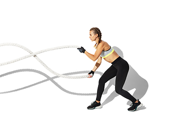 Image showing Beautiful young female athlete practicing on white studio background with shadows