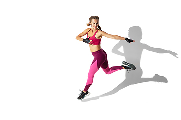 Image showing Beautiful young female athlete practicing on white studio background with shadows