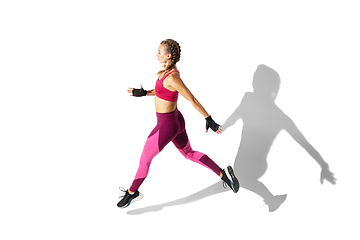 Image showing Beautiful young female athlete practicing on white studio background with shadows