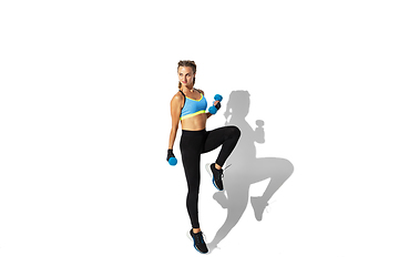 Image showing Beautiful young female athlete practicing on white studio background with shadows