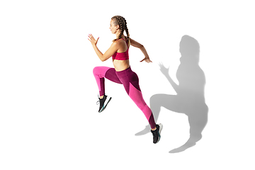 Image showing Beautiful young female athlete practicing on white studio background with shadows