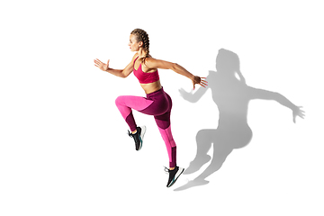 Image showing Beautiful young female athlete practicing on white studio background with shadows