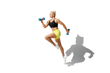 Image showing Beautiful young female athlete practicing on white studio background with shadow