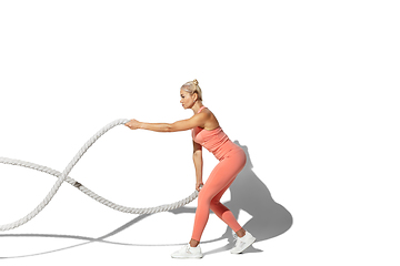 Image showing Beautiful young female athlete practicing on white studio background with shadow