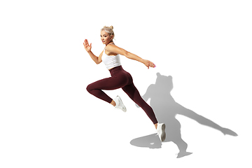 Image showing Beautiful young female athlete practicing on white studio background with shadow