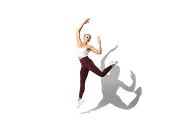 Image showing Beautiful young female athlete practicing on white studio background with shadow