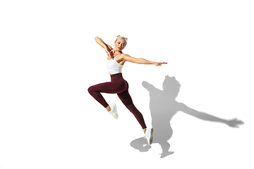 Image showing Beautiful young female athlete practicing on white studio background with shadow
