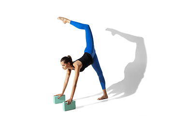 Image showing Beautiful young female athlete stretching on white studio background with shadows