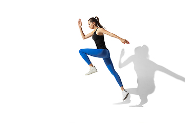 Image showing Beautiful young female athlete stretching on white studio background with shadows