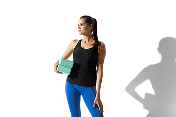 Image showing Beautiful young female athlete stretching on white studio background with shadows