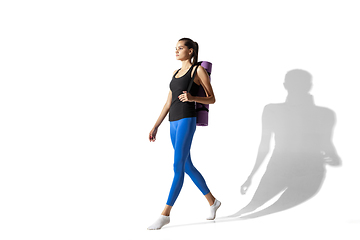 Image showing Beautiful young female athlete stretching on white studio background with shadows