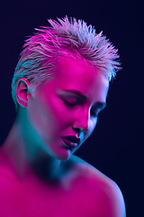 Image showing Portrait of female fashion model in neon light on dark studio background.