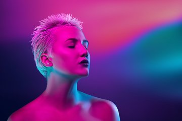 Image showing Portrait of female fashion model in neon light on dark studio background.