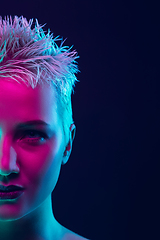 Image showing Portrait of female fashion model in neon light on dark studio background.