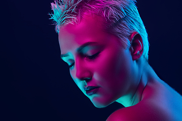 Image showing Portrait of female fashion model in neon light on dark studio background.