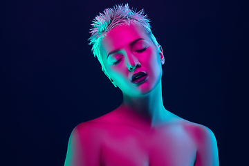 Image showing Portrait of female fashion model in neon light on dark studio background.