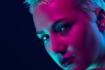 Image showing Portrait of female fashion model in neon light on dark studio background.