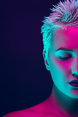 Image showing Portrait of female fashion model in neon light on dark studio background.