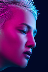 Image showing Portrait of female fashion model in neon light on dark studio background.