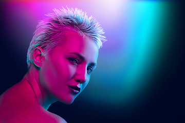 Image showing Portrait of female fashion model in neon light on dark studio background.