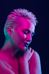 Image showing Portrait of female fashion model in neon light on dark studio background.