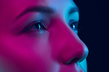 Image showing Portrait of female fashion model in neon light on dark studio background.