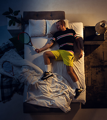 Image showing Top view of young professional tennis player sleeping at his bedroom in sportwear with racket