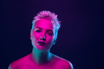 Image showing Portrait of female fashion model in neon light on dark studio background.