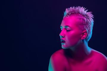 Image showing Portrait of female fashion model in neon light on dark studio background.