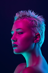 Image showing Portrait of female fashion model in neon light on dark studio background.