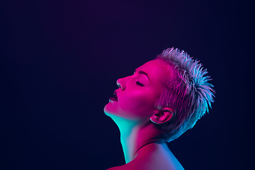 Image showing Portrait of female fashion model in neon light on dark studio background.