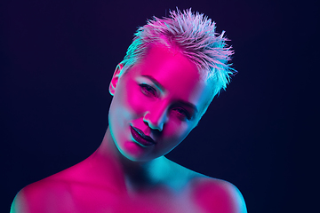 Image showing Portrait of female fashion model in neon light on dark studio background.