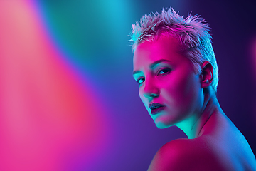 Image showing Portrait of female fashion model in neon light on dark studio background.