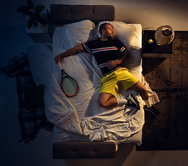 Image showing Top view of young professional tennis player sleeping at his bedroom in sportwear with racket