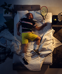 Image showing Top view of young professional tennis player sleeping at his bedroom in sportwear with racket